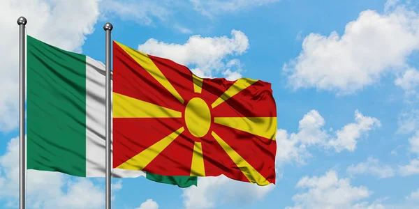 Nigéria e Macedônia acenando com o vento contra o céu azul nublado branco juntos. Conceito de diplomacia, relações internacionais . — Fotografia de Stock