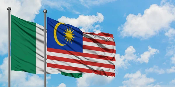 尼日利亚和马来西亚国旗在风中飘扬，与白云蓝天相一起。外交概念、国际关系. — 图库照片