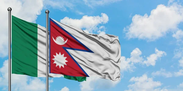Bandera de Nigeria y Nepal ondeando en el viento contra el cielo azul nublado blanco juntos. Concepto diplomático, relaciones internacionales . — Foto de Stock