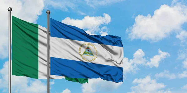 Nigeria und Nicaragua schwenken gemeinsam die Flagge im Wind gegen den wolkenverhangenen blauen Himmel. Diplomatie-Konzept, internationale Beziehungen. — Stockfoto