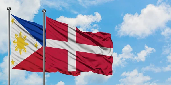 Bandera de Filipinas y Dinamarca ondeando en el viento contra el cielo azul nublado blanco juntos. Concepto diplomático, relaciones internacionales . — Foto de Stock
