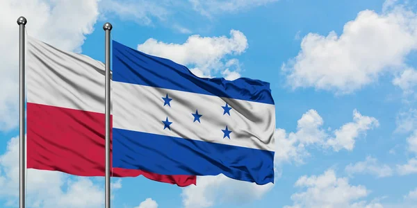 A bandeira da Polônia e Honduras agitando no vento contra o céu azul nublado branco juntos. Conceito de diplomacia, relações internacionais . — Fotografia de Stock