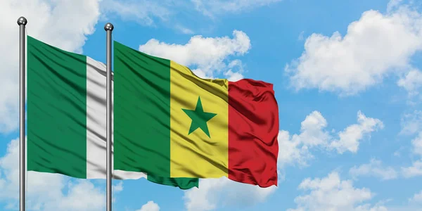 Nigeria och Senegal flagga vifta i vinden mot vit grumlig blå himmel tillsammans. Diplomatisk koncept, internationella relationer. — Stockfoto