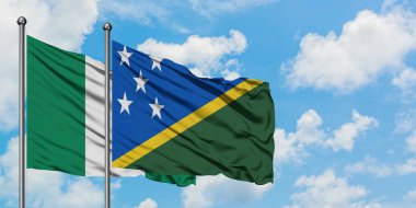 Nijerya ve Solomon Adaları bayrağı birlikte beyaz bulutlu mavi gökyüzüne karşı rüzgarda sallayarak. Diplomasi kavramı, uluslararası ilişkiler.