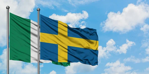 Флаг Нигерии и Швеции, размахивающий ветром против белого облачного голубого неба вместе взятого. Концепция дипломатии, международные отношения . — стоковое фото