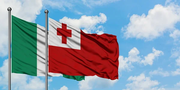 Bandera de Nigeria y Tonga ondeando en el viento contra el cielo azul nublado blanco juntos. Concepto diplomático, relaciones internacionales . — Foto de Stock