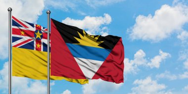 Niue ve Antigua ve Barbuda bayrağı birlikte beyaz bulutlu mavi gökyüzüne karşı rüzgarda sallayarak. Diplomasi kavramı, uluslararası ilişkiler.
