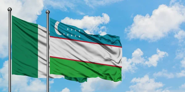 Nigéria e Uzbequistão bandeira acenando no vento contra o céu azul nublado branco juntos. Conceito de diplomacia, relações internacionais . — Fotografia de Stock