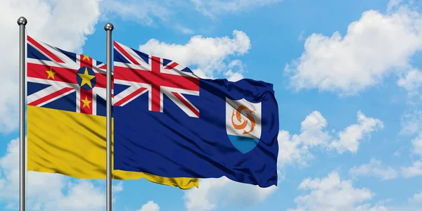 Vlajka Niue a Anguilla mávaje ve větru proti bíle zatažené modré obloze. Diplomacie, mezinárodní vztahy. — Stock fotografie