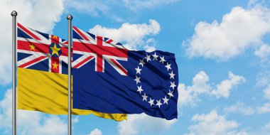 Niue ve Cook Adaları bayrak birlikte beyaz bulutlu mavi gökyüzüne karşı rüzgarda sallayarak. Diplomasi kavramı, uluslararası ilişkiler.