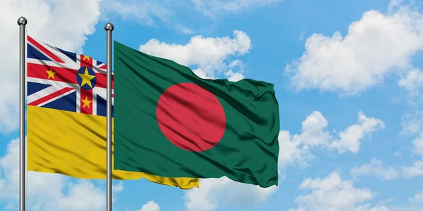 Bandera de Niue y Bangladesh ondeando en el viento contra el cielo azul nublado blanco juntos. Concepto diplomático, relaciones internacionales . — Foto de Stock