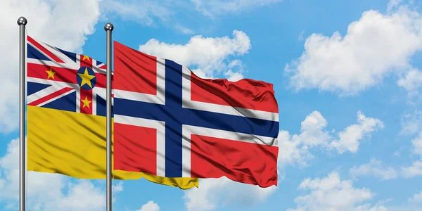 Bandera de las islas Niue y Bouvet ondeando en el viento contra el cielo azul nublado blanco juntos. Concepto diplomático, relaciones internacionales . — Foto de Stock