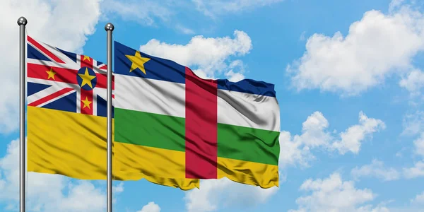 Bandera de Niue y República Centroafricana ondeando en el viento contra el cielo azul nublado blanco juntos. Concepto diplomático, relaciones internacionales . — Foto de Stock