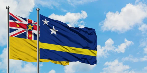 纽埃和库拉索旗在风中飘扬，白云蓝天相聚。外交概念、国际关系. — 图库照片
