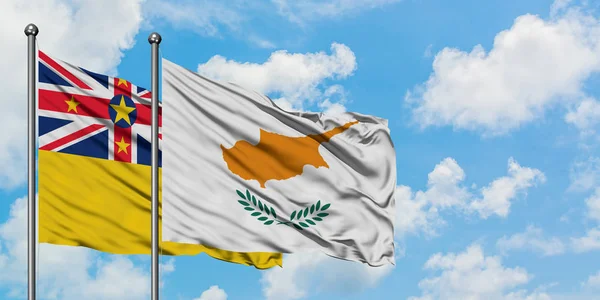 Bandera de Niue y Chipre ondeando en el viento contra el cielo azul nublado blanco juntos. Concepto diplomático, relaciones internacionales . — Foto de Stock