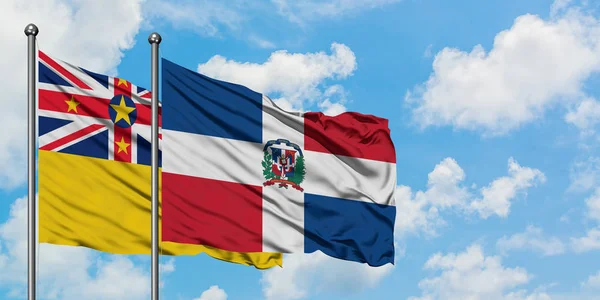 Niue e Repubblica Dominicana bandiera sventolando nel vento contro bianco cielo blu nuvoloso insieme. Concetto di diplomazia, relazioni internazionali . — Foto Stock
