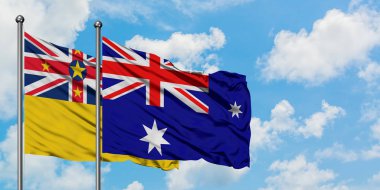 Niue ve Heard Adası ve Mcdonald Adaları bayrağı birlikte beyaz bulutlu mavi gökyüzüne karşı rüzgarda sallayarak. Diplomasi kavramı, uluslararası ilişkiler.