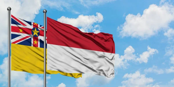 Bandera de Niue e Indonesia ondeando en el viento contra el cielo azul nublado blanco juntos. Concepto diplomático, relaciones internacionales . — Foto de Stock