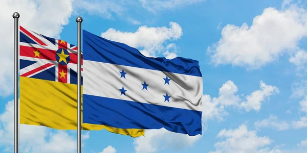 Ніуе і Гондурас прапор розмахував вітром проти білого хмарного синього неба разом. Концепція дипломатії, міжнародні відносини. — стокове фото