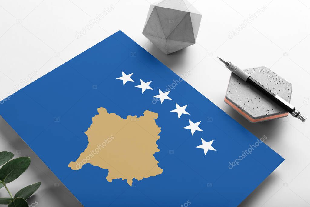 Kosovo flag on minimalist paper background. National invitation letter with stylish pen on stone. Communication concept.