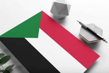 Minimalist kağıt üzerinde Sudan bayrağı. Taşın üzerinde zarif bir kalemle ulusal davetiye mektubu. İletişim konsepti.