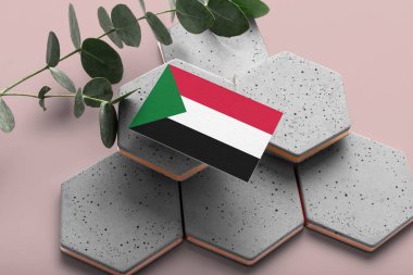 Altıgen taşlarda Sudan bayrağı. Pembe kopyalama alanı arka planı. Düzlük, üst görünüm asgari ulusal kavram.