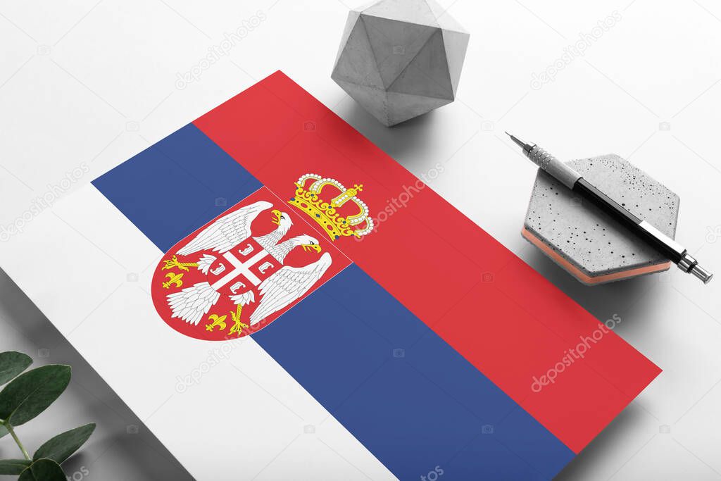 Serbia flag on minimalist paper background. National invitation letter with stylish pen on stone. Communication concept.