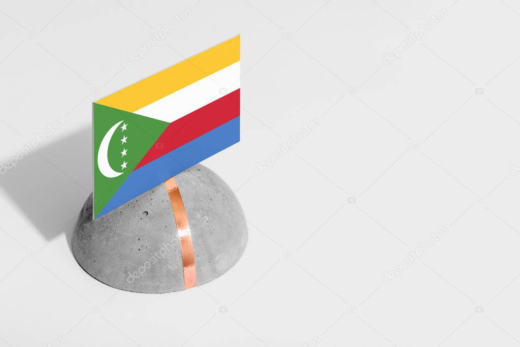 Comoros flag tagged on rounded stone. White isolated background. Side view minimal national concept.