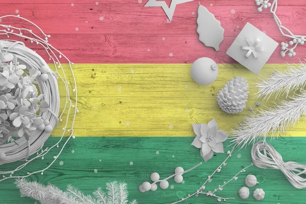 Bolivia flag on wooden table with snow objects. Christmas and new year background, celebration national concept with white decor.