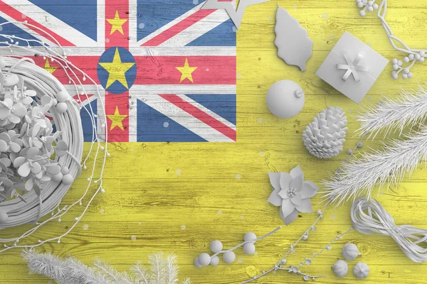 Niue flag on wooden table with snow objects. Christmas and new year background, celebration national concept with white decor.