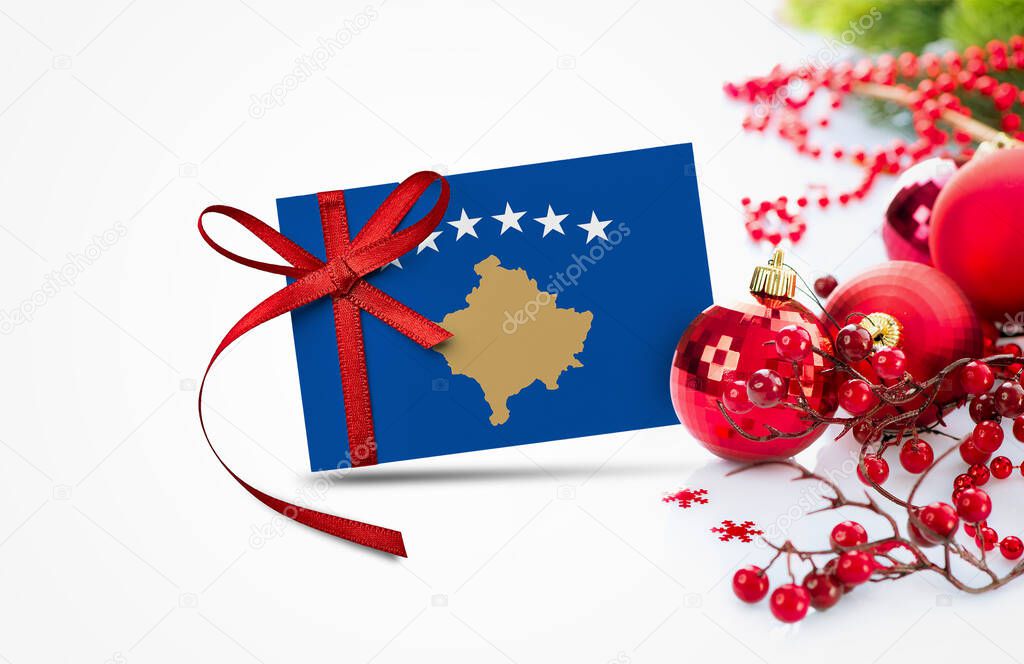Kosovo flag on new year invitation card with red christmas ornaments concept. National happy new year composition.