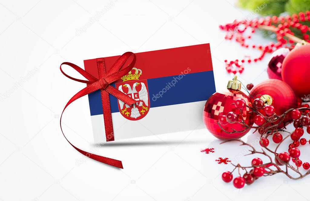 Serbia flag on new year invitation card with red christmas ornaments concept. National happy new year composition.