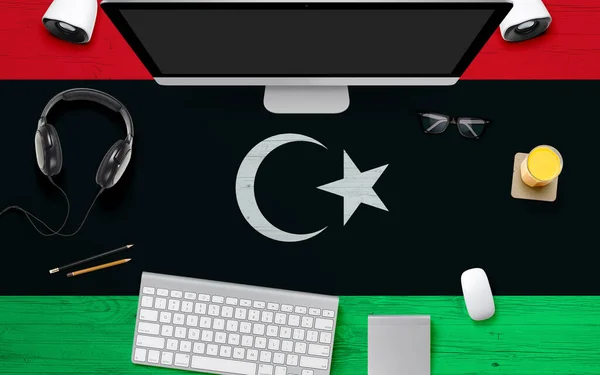 Libya flag background with headphone,computer keyboard and mouse on national office desk table.Top view with copy space.Flat Lay.