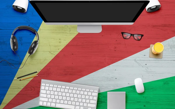 Seychelles flag background with headphone,computer keyboard and mouse on national office desk table.Top view with copy space.Flat Lay.