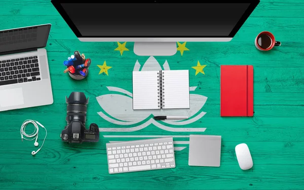 Macao flag background with headphone,camera, notebook and mouse on national office desk table.Top view with copy space.Flat Lay.