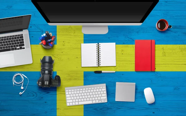 Sweden flag background with headphone,camera, notebook and mouse on national office desk table.Top view with copy space.Flat Lay.