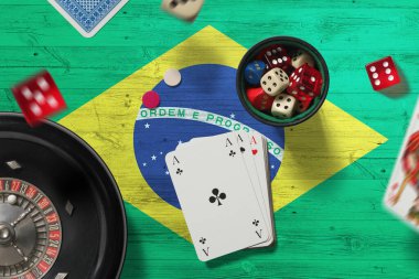 Brezilya kumarhanesi teması. Pokerdeki aslar, kırmızı masada ulusal bayrak geçmişi olan kartlar ve çipler. Kumar ve bahis.