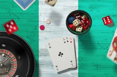 Nijerya Kumarhanesi teması. Pokerdeki aslar, kırmızı masada ulusal bayrak geçmişi olan kartlar ve çipler. Kumar ve bahis.