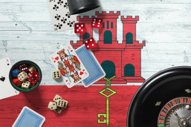 Cebelitarık kumarhanesi teması. Pokerdeki aslar, kırmızı masada ulusal tahta bayraklı kartlar ve fişler. Kumar ve bahis.