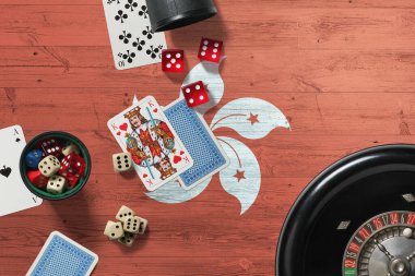 Hong Kong kumarhanesi teması. Pokerdeki aslar, kırmızı masada ulusal tahta bayraklı kartlar ve fişler. Kumar ve bahis.