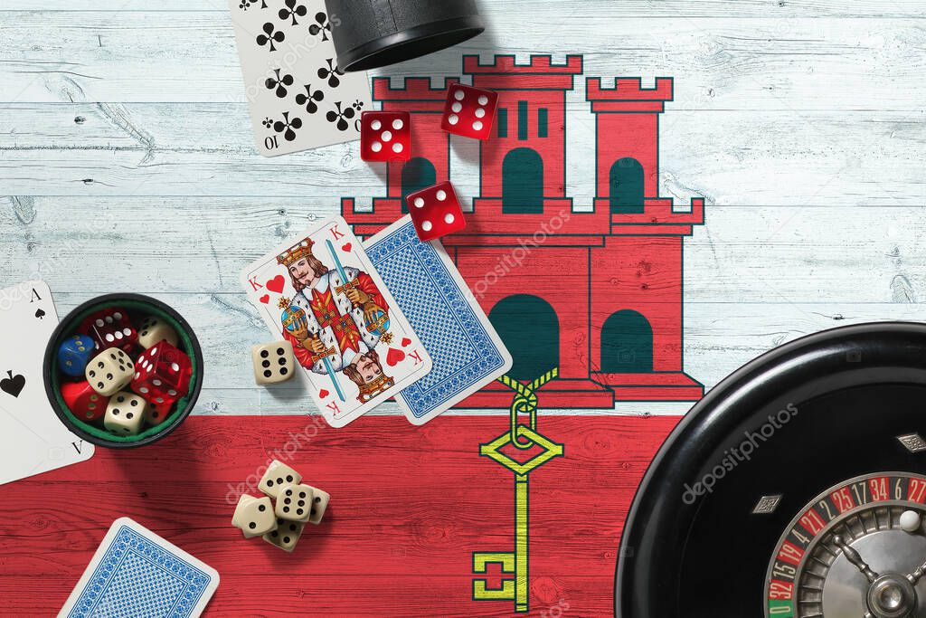 Gibraltar casino theme. Aces in poker game, cards and chips on red table with national wooden flag background. Gambling and betting.