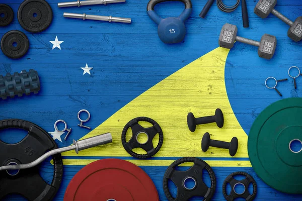 Tokelau spor ve spor konsepti. Ulusal arkaplanda demir çubuk bulunan ağır ağırlık plakalarının üst görünümü.