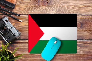 Ahşap zemin üzerinde Filistin bayrağı ve fare altlığı üzerinde mavi kablosuz fare, üst manzara. Dijital ortam kavramı.
