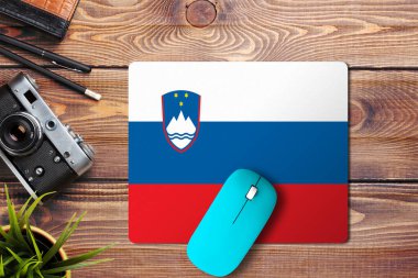 Slovenya bayrağı ahşap zemin üzerinde mavi kablosuz fare ile bir fare altlığı, üst manzara. Dijital ortam kavramı.