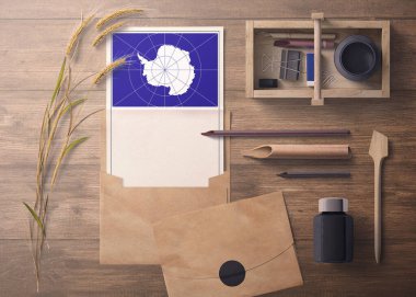 Antarktika daveti, kutlama mektubu konsepti. El işi kâğıdı ve zarflı bayrak. Bölme, mürekkep, tahta kalem nesneleri ile geçmişe dönük tema.