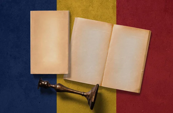 Romania vintage historical concept. Retro craft papers and old wooden candlestick on national flag wall background.
