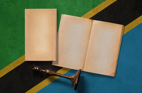 Tanzania vintage historical concept. Retro craft papers and old wooden candlestick on national flag wall background.