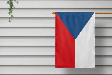 Czech Republic national small flag hangs from a picket fence along the wooden wall in a rural town. Independence day concept. clipart