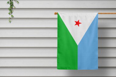 Cibuti ulusal bayrağı, kırsal bir kasabanın ahşap duvarı boyunca asılı duran çitten sarkıyor. Bağımsızlık Günü kavramı.