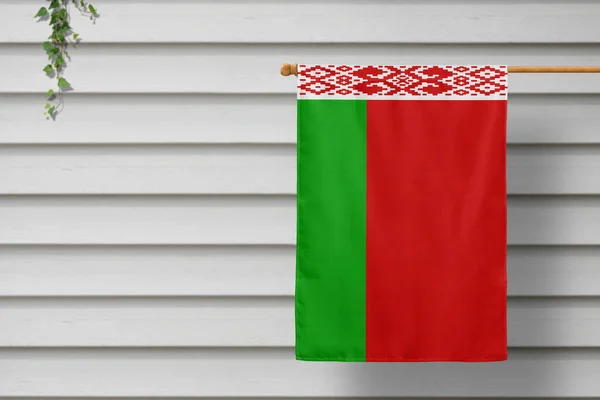 Belarus national small flag hangs from a picket fence along the wooden wall in a rural town. Independence day concept.